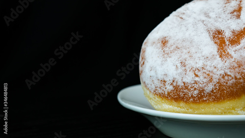 Donuts with sugar on a white plate and black background. Isolated donuts in horizontal photo