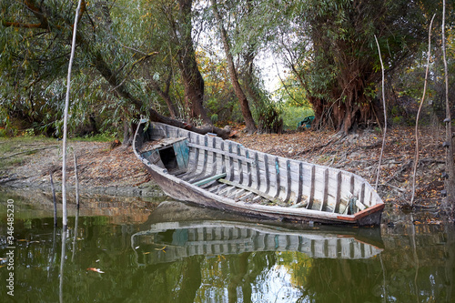 Old broken wooden fishing boat on the river shore at autumn photo