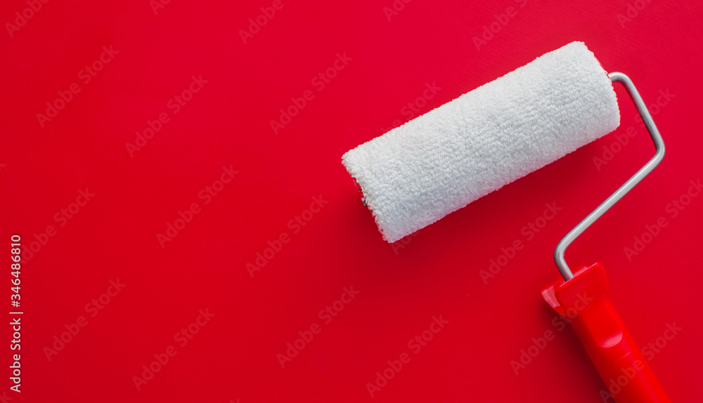Obraz premium The concept of construction malar works. New clean white paint roller on a red background. Copy space