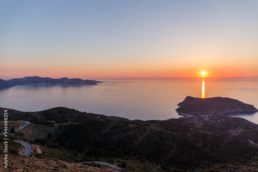 sunset at sea seen from a viewpoint in Kefalonia, Greek island, the water is calm and the sky takes on orange tones