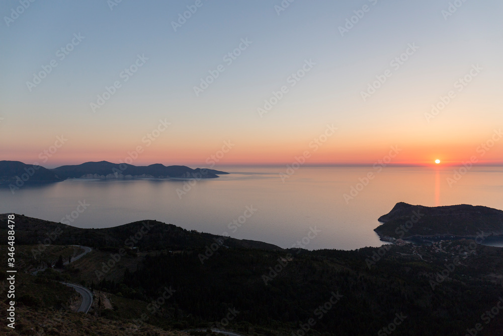 sunset at sea seen from a viewpoint in Kefalonia, Greek island, the water is calm and the sky takes on orange tones