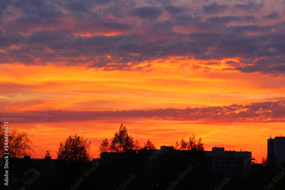 yellow-orange sunset with purple clouds over the city