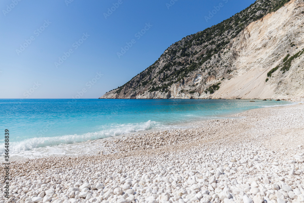 Beach with crystal clear turquoise water and white stones, waves at Myrtos beach, Kefalonia island, Greece