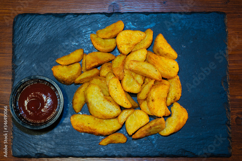 French fries cooked in a deep fryer with sauce on a black stone tray