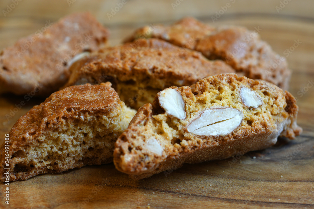 Closeup on Cantucci or Cantuccini on wooden background. Cantuccini are typical Tuscan dry biscuits, made with flour, eggs, yeast and almonds. Italy.