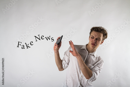 Young man holding smartphone in his hands. Antipathy, dislike and refuse concept. Fake news.