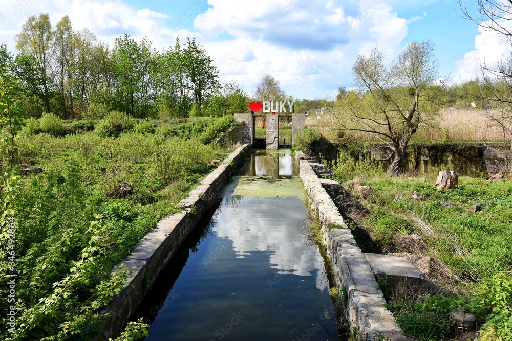 Fototapeta premium The inscription Buky with a red heart over the dam near the canyon. Nature reserve. Sights of Ukraine. Domestic tourism. granite canyon Buki Cherkasy region, Ukraine. Ukrainian landmarks. 