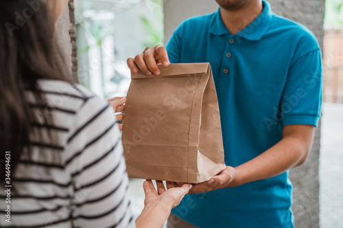 Delivery man delivering food to a woman at home. online food shopping service concept