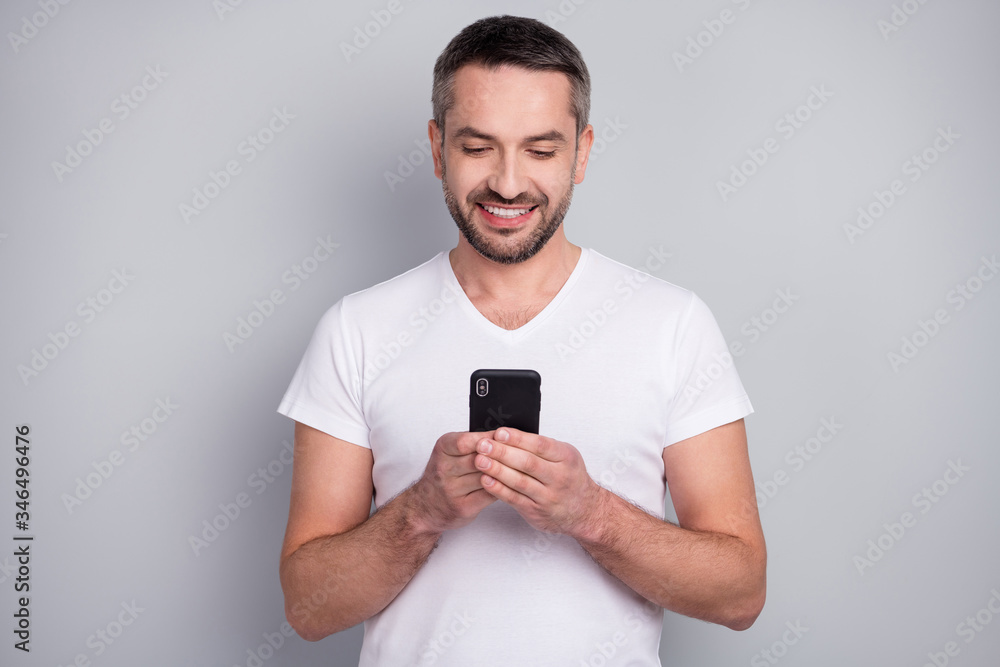 Close-up portrait of his he nice attractive focused cheerful cheery guy using digital device gadget chatting isolated over light grey pastel color background Close-up portrait of his he nice attractive focused cheerful cheery guy using digital device gadget chatting isolated over light grey pastel color background