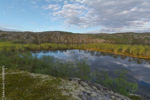 The reservoir is surrounded by hills and forest.Clouds are reflected in the water.Summer landscape.