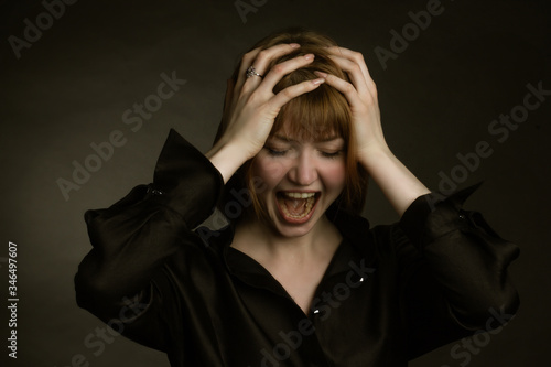 Portrait of redheaded girl. holding his hands behind his head and hysteria