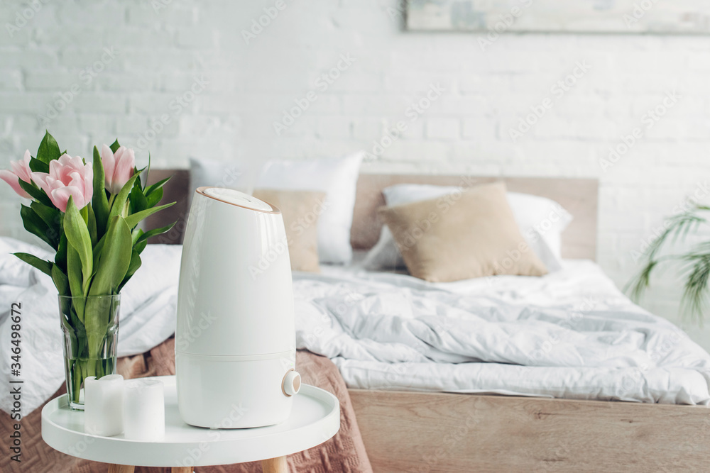 white ultrasonic purifier, tulips and candles on table in bedroom