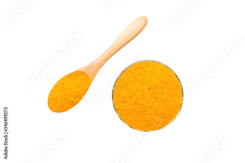 Turmeric powder in glass bowl and wooden spoon isolated on white background.