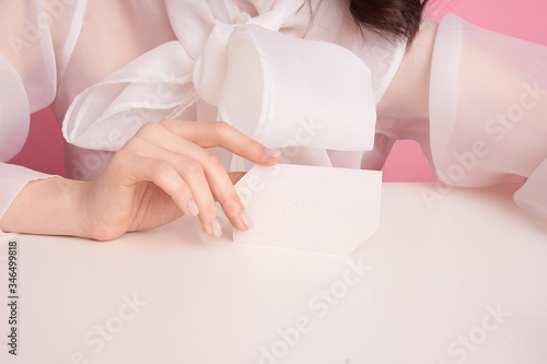  close-up female hand on a pink background holds an empty sheet to fill