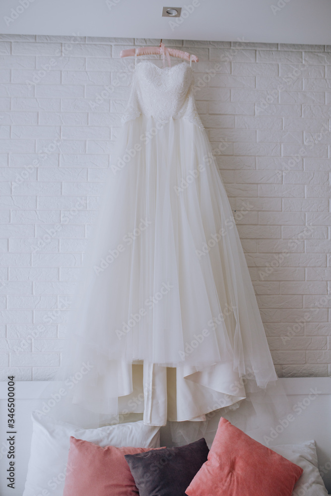 White wedding dress hanging on the wall in the room
White wedding dress hanging on the wall in the room