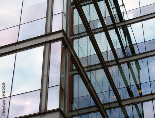 full frame modern office architecture angular abstract with geometric shapes and blue sky reflected in glass windows