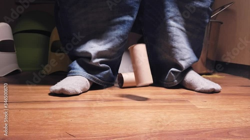Feet of person on toilet as empty toilet paper rolls fall to ground photo