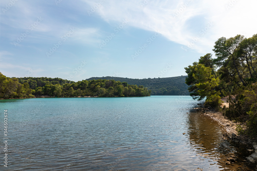 View of the saltwater blue colored lakes of malo and veliko jezero at the National Park on the island Mljet, Croatia. Mediterranean adriatic coast with a blue sky and greenery