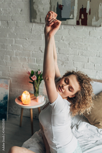 beautiful girl stretching in cozy bedroom with Himalayan salt lamp