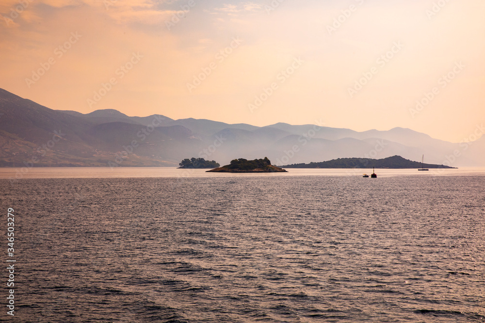 Fototapeta premium Small islands with boats in the mediterreanean adriatic sea on a sunny day calm and peaceful mindful nature and mountains in the background
