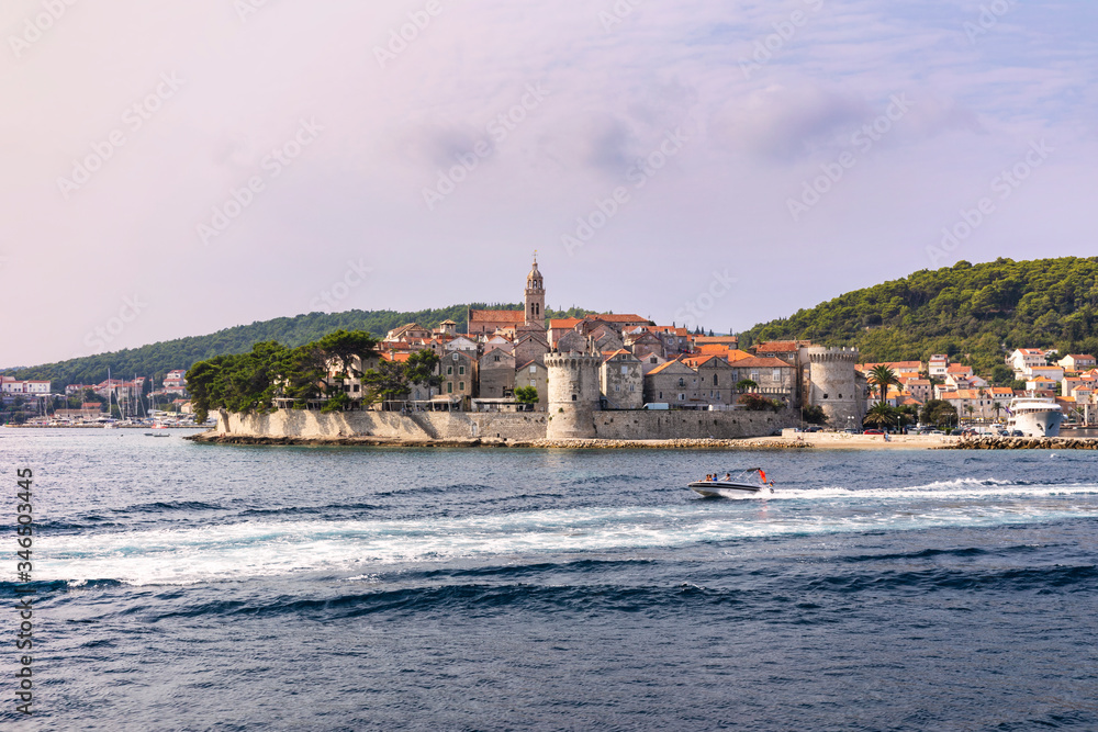 Naklejka premium Korcula island with the old city walls, view from the sea on a sunny day in the summer blue sky. Clear Adriatic sea, the south mediterranean coast of Croatia Europe. 