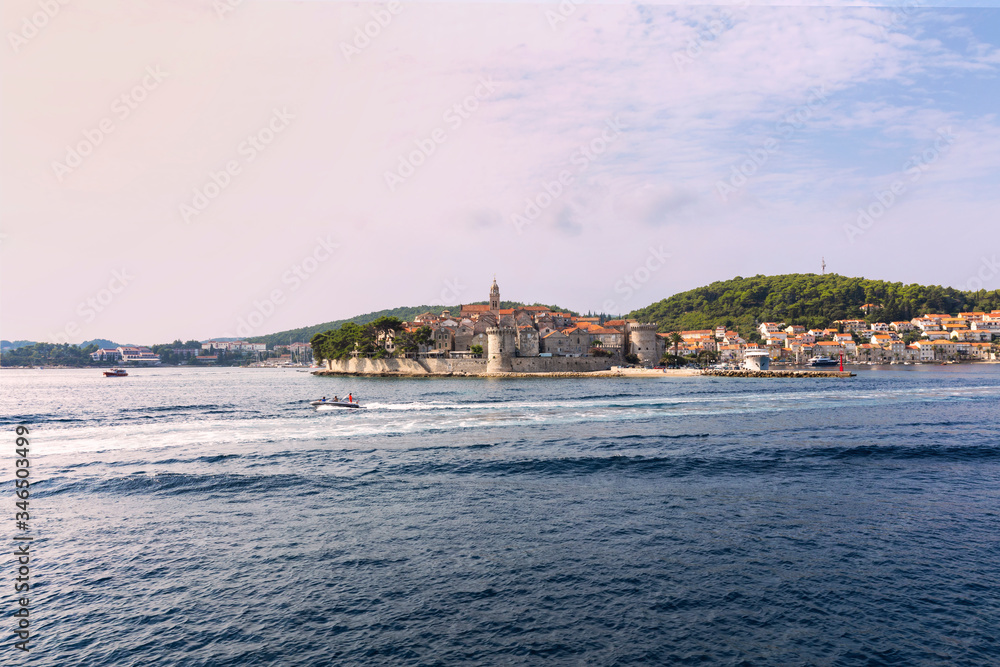 Korcula island with the old city walls, view from the sea on a sunny day in the summer blue sky. Clear adriactic sea, the south mediterranean coast of Croatia Europe. Beautiful landscape with greenery Korcula island with the old city walls, view from the sea on a sunny day in the summer blue sky. Clear adriactic sea, the south mediterranean coast of Croatia Europe. Beautiful landscape with greenery