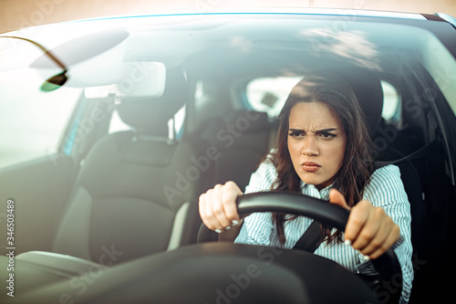Angry woman driving a car. The girl with an expression of displeasure is actively gesticulating behind the wheel of the car. Angry business woman in a car. Stress girl in a car © Dragana Gordic