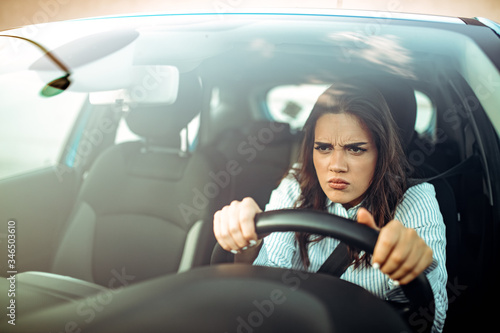 Road rage! Enraged young woman driver shouts and points accusingly.  Profile of an angry young driver. Negative human emotions face expression. Angry woman driving a car © Dragana Gordic