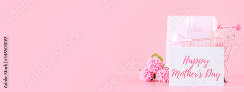 Mother's Day holiday gift design concept, pink carnation flower bouquet with wrapped box isolated on light pink background, copy space. © RomixImage