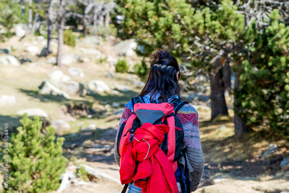 Rear view of a backpacker woman hiking Rear view of a backpacker woman hiking