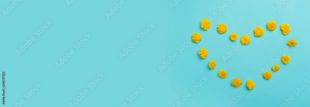 Fresh flowers in the shape of a heart on a blue background. Natural cosmetic.
