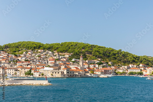 Pucisca town at Brac in Croatia, view from the sea on a sunny day in the summer. The port with it’s famous limestone from the island. Idyllic place, white stone creating a beautiful scenery