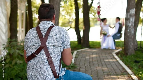 Wedding photographer taking pictures couple of newlyweds on a rope swing
