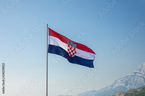 Fotografie The red white blue Croatian flag waving in the wind on a flagpole on a sunny day