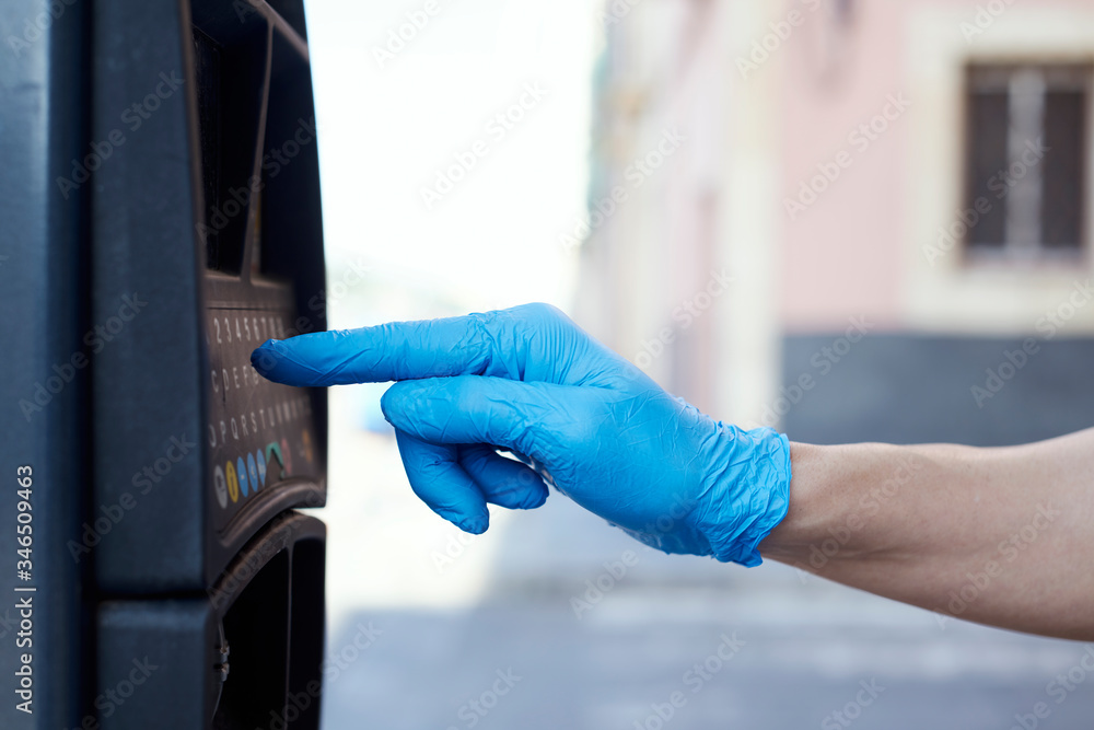 man wearing latex gloves using a parking meter
