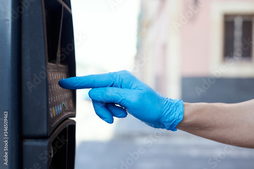 man wearing latex gloves using a parking meter