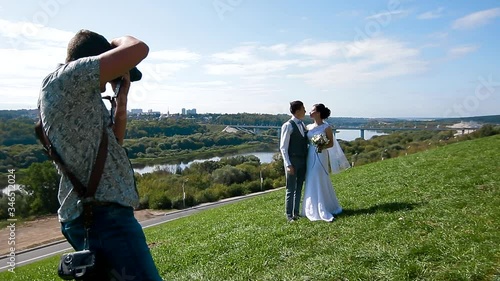 Wedding photographer taking pictures of the bride and groom on a hillside