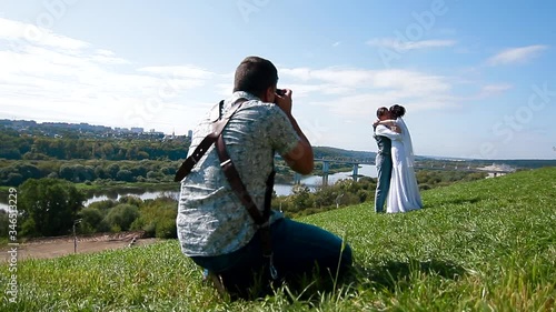 Wedding photographer taking pictures of the bride and groom on a hillside