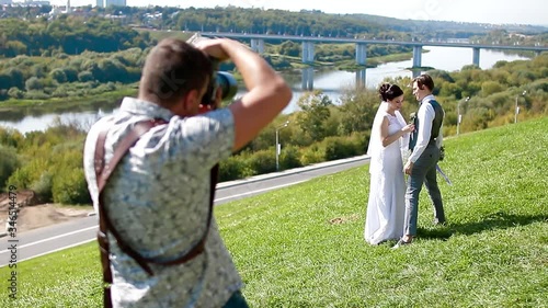 Wedding photographer taking pictures of the bride and groom on a hillside