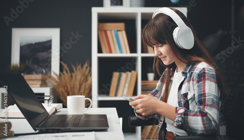 Canvas Print Side view of female teenager using digital gadgets sitting at table while studyi
