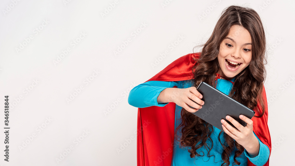 Girl with hero costume playing on tablet Girl with hero costume playing on tablet