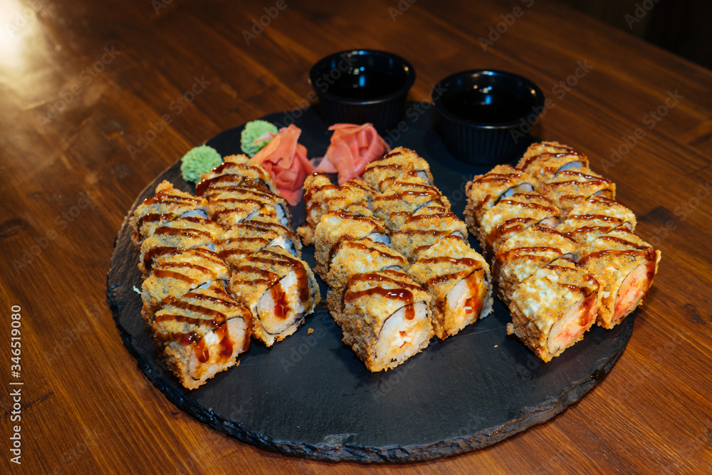 A set of sushi. Philadelphia roll, California, unagi, black dragon with fresh ingredients. The sushi menu. Japanese cuisine. Ginger and wasabi. Soy sauce. Sesame. Hot, baked, breaded