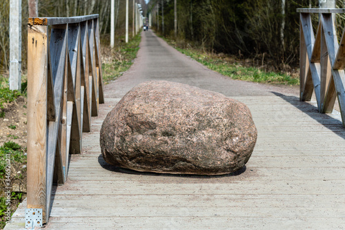 a large stone lies in the middle of a wooden bridge. Against the background of the forest and the river. photo