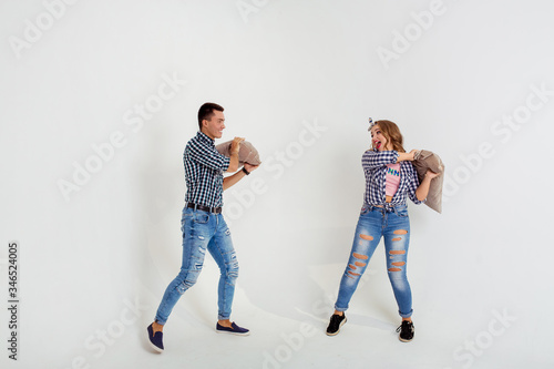 a man and a woman are fighting with pillows, standing in full height, very fun, laughing, European appearance