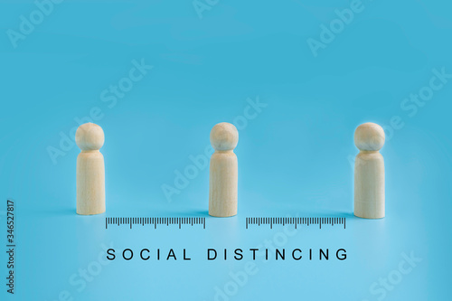 Wooden dolls on blue background with distancing and measure scale. people practice social distancing to protect from COVID-19 coronavirus spreading. Social distance preventing infection concept.