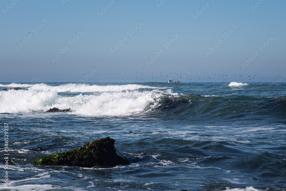 A calm and peaceful landscape. Beautiful nautical scene in blue tones. An ideal place to enjoy the sea view. Seagulls fly over ocean waves.