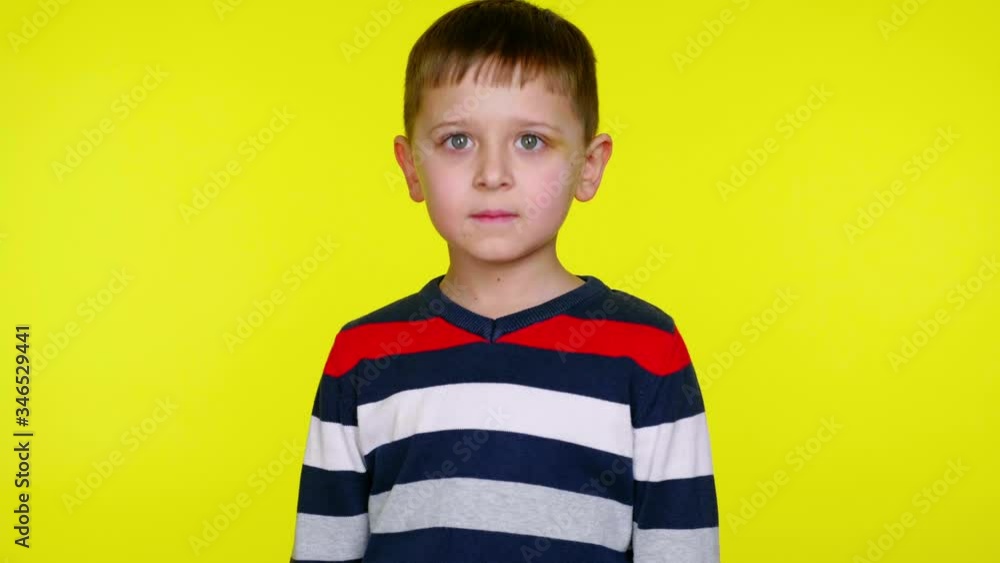 Serious little child boy in a colorful sweater says yes on a yellow background with copy space. Place for text or product. 4K slowmotion footage Serious little child boy in a colorful sweater says yes on a yellow background with copy space. Place for text or product. 4K slowmotion footage
