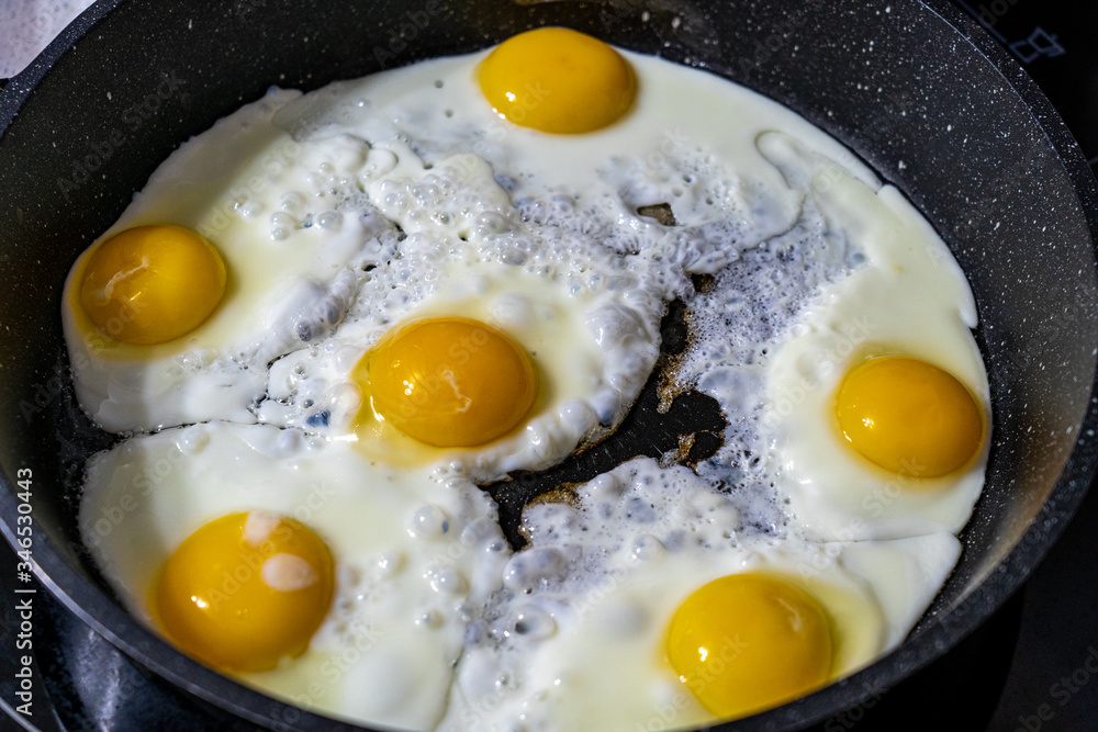 Closeup view of fried eggs which are being cooked on black frying pan in the morning at kitchen Closeup view of fried eggs which are being cooked on black frying pan in the morning at kitchen