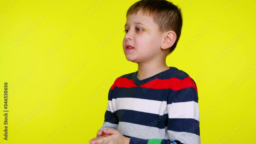 Sick little boy sneezes and covers his mouth with palms on a yellow background with copy space. Little child in a colorful sweater. Place for text or product. 4K slowmotion footage Sick little boy sneezes and covers his mouth with palms on a yellow background with copy space. Little child in a colorful sweater. Place for text or product. 4K slowmotion footage