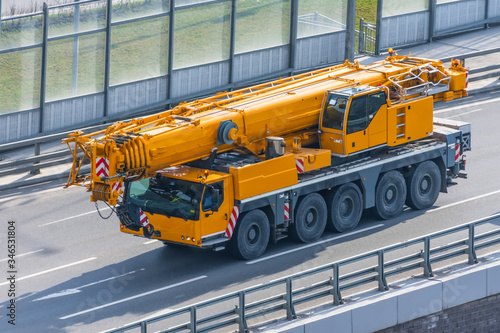 Heavy mobile crane with folding boom construction rides on a city highway. photo